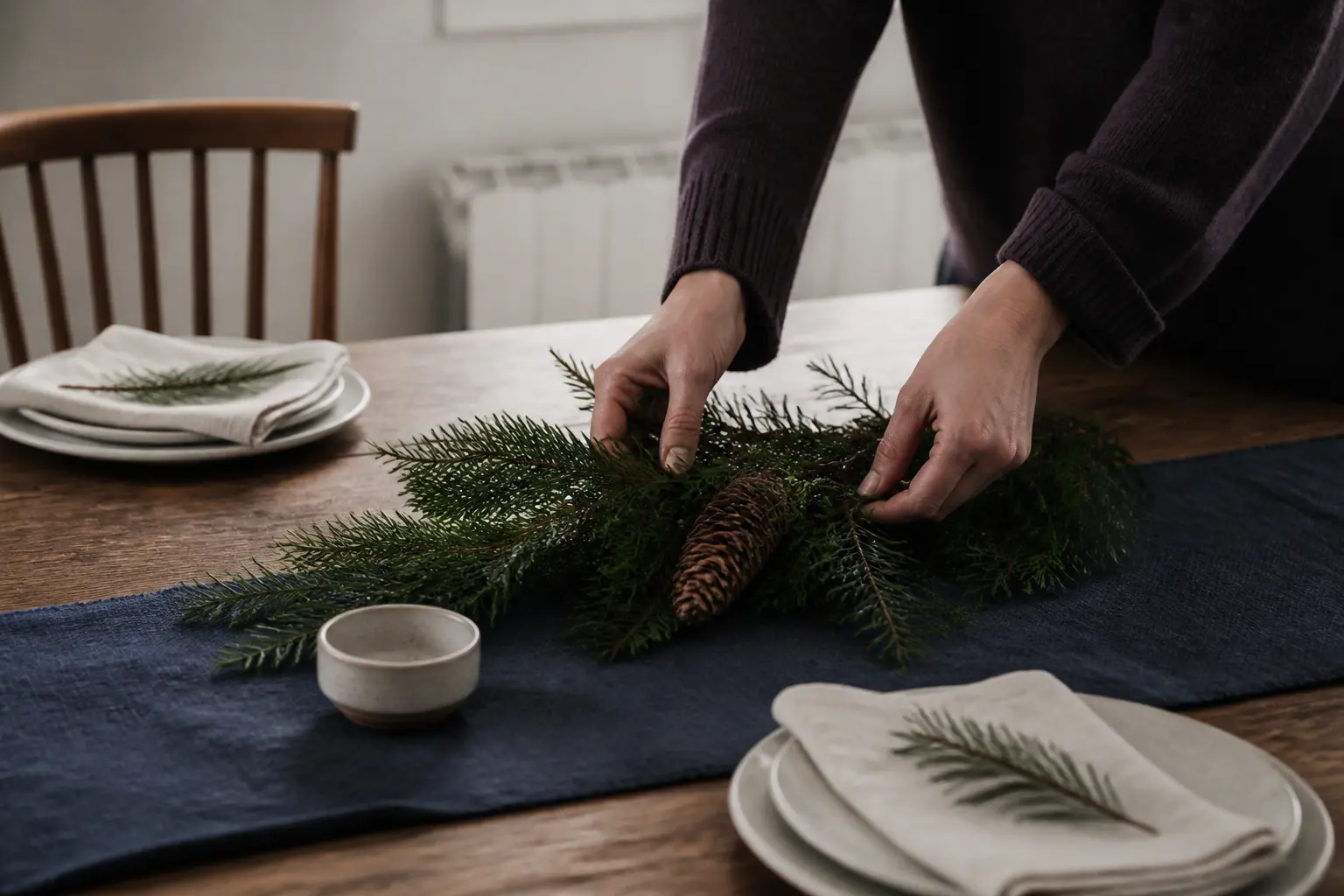Mains décorant une deco table noel a faire soi meme, centre de table simple sur table de salle à manger, lumière douce naturelle