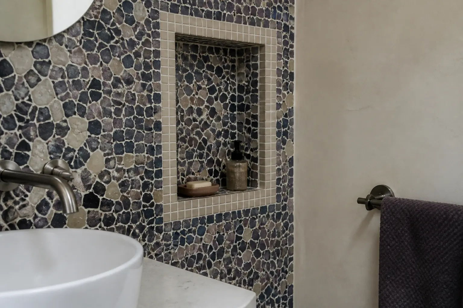 Mosaique dans salle de bain : crédence en petits carreaux autour d’un lavabo, niche murale et lumière naturelle douce